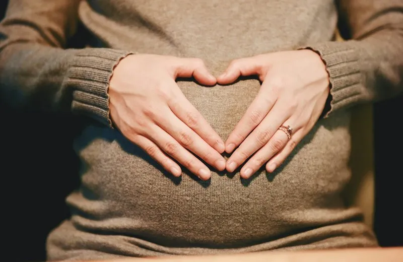 Hands making a heart over a pregnant belly