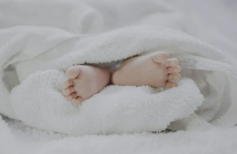 Newborn baby feet in a white blanket