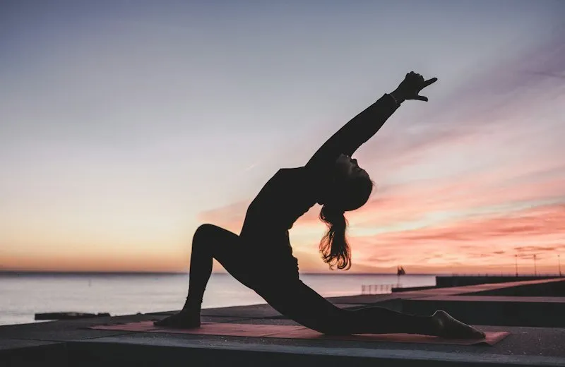 Woman doing a yoga stretch at sunset